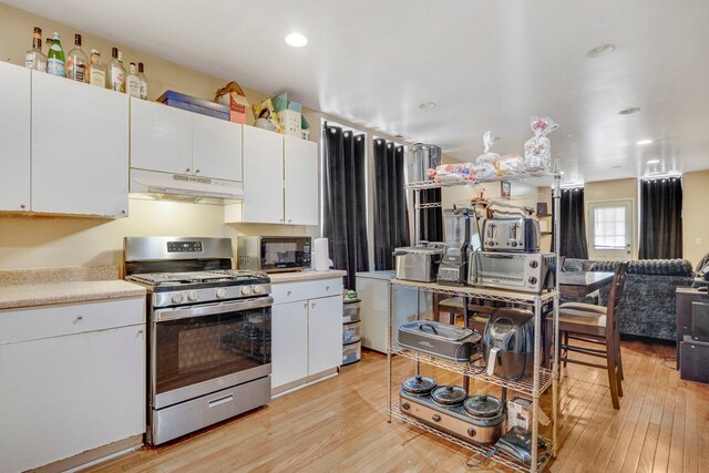 1234 S Karlov Ave, Chicago, IL 60623 - kitchen featuring under cabinet range hood, light wood-style floors, white cabinetry, and stainless steel range with gas cooktop