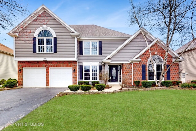 view of front of house with an attached garage, driveway, a front yard, and brick siding