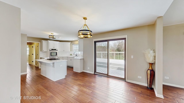 kitchen with light countertops, white cabinetry, hardwood / wood-style floors, oven, and a sink
