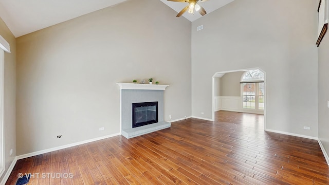 unfurnished living room featuring high vaulted ceiling, a brick fireplace, wood finished floors, and ceiling fan