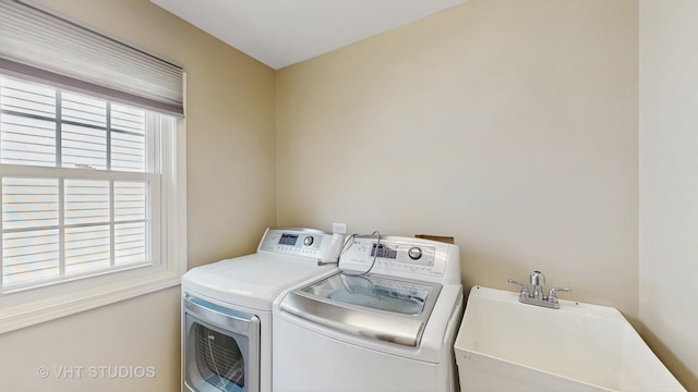 clothes washing area featuring washer and clothes dryer, laundry area, and a sink