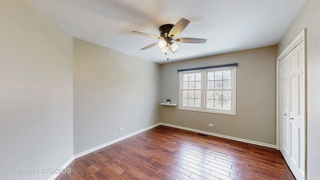 unfurnished bedroom featuring a closet, ceiling fan, baseboards, and dark wood-style floors
