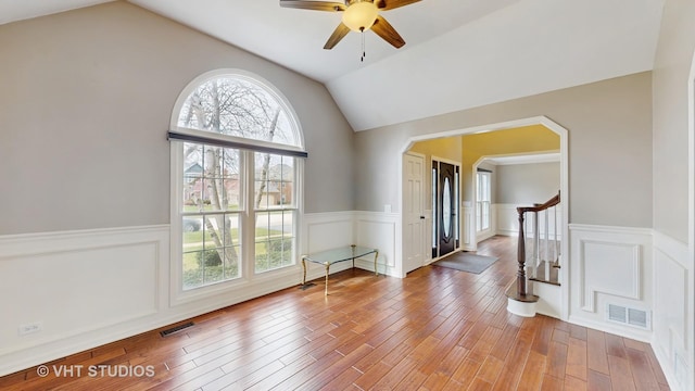 spare room with vaulted ceiling, visible vents, and a wainscoted wall
