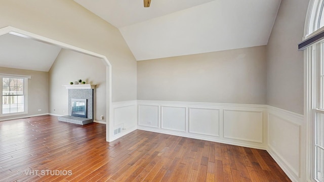 unfurnished living room with a brick fireplace, wood finished floors, and vaulted ceiling