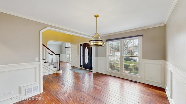 unfurnished dining area featuring a notable chandelier, stairs, visible vents, and a wainscoted wall