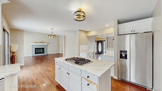 kitchen featuring white cabinets, a kitchen island, stainless steel appliances, open floor plan, and hardwood / wood-style flooring