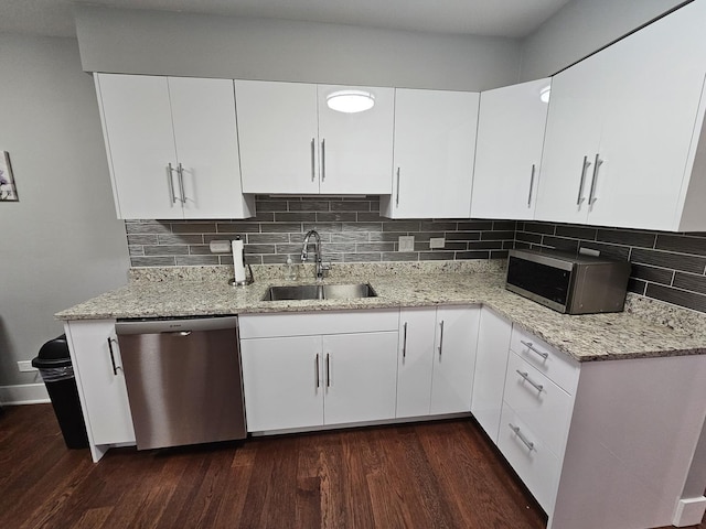 kitchen with tasteful backsplash, light stone countertops, dark wood finished floors, stainless steel appliances, and a sink