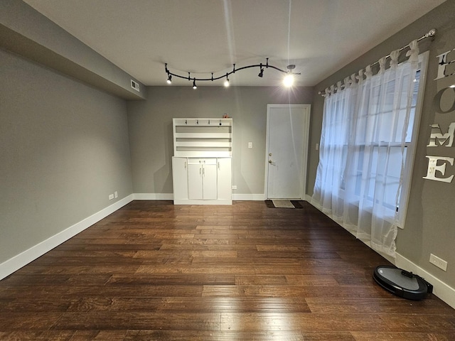 unfurnished dining area featuring dark wood-style flooring, visible vents, baseboards, and track lighting