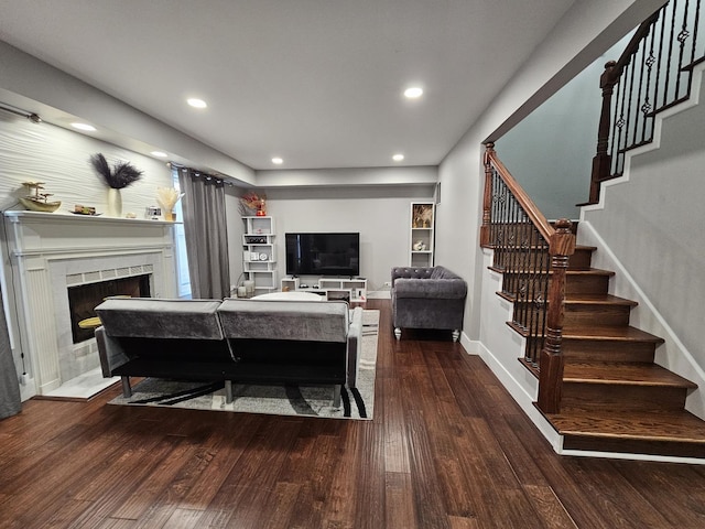 living room featuring wood finished floors, a tile fireplace, recessed lighting, and stairway