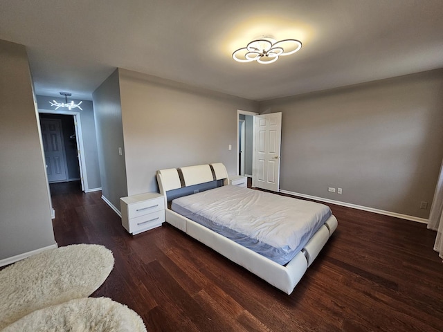 bedroom with wood finished floors, a notable chandelier, and baseboards