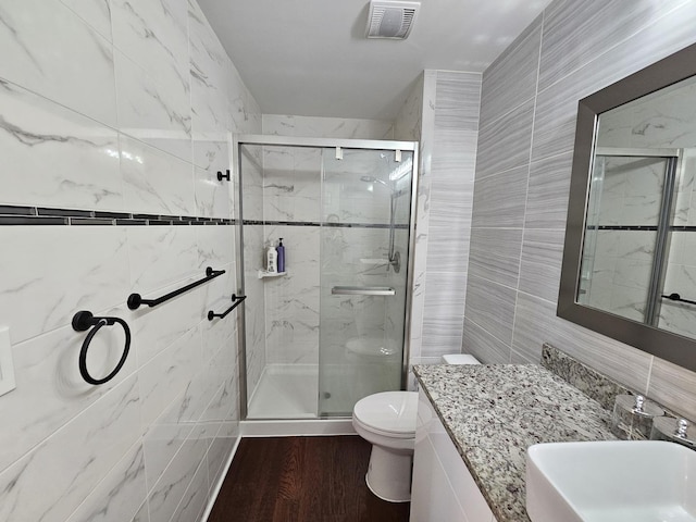 bathroom with toilet, visible vents, tile walls, and a stall shower