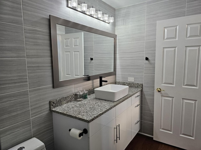 half bath featuring vanity and tile walls