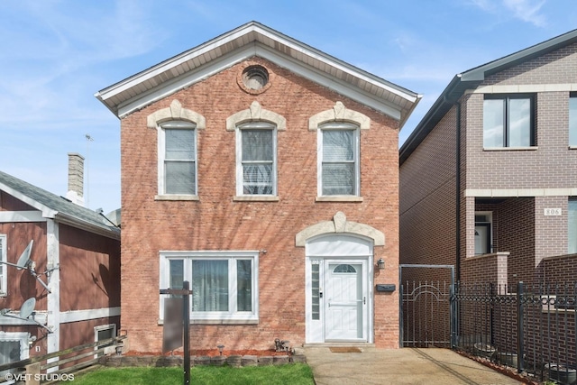 view of front facade featuring brick siding, fence, and a gate