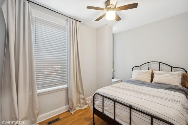 bedroom featuring visible vents, baseboards, light wood-type flooring, and ceiling fan
