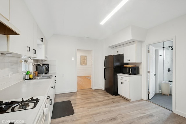 kitchen featuring tasteful backsplash, light countertops, white cabinets, light wood-style floors, and black appliances