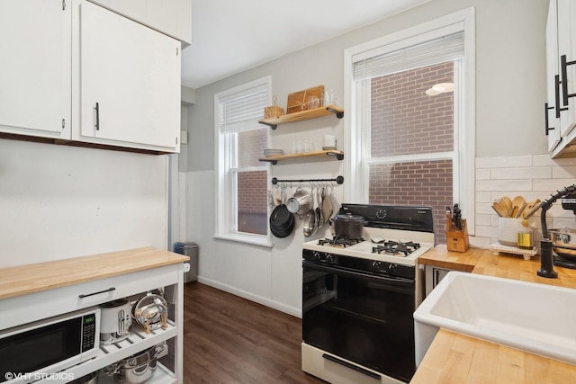 kitchen featuring butcher block counters, white cabinetry, a sink, gas range oven, and decorative backsplash