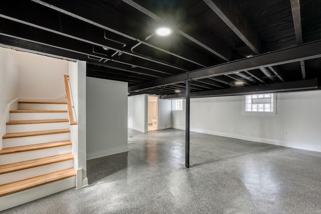 basement featuring baseboards and stairs