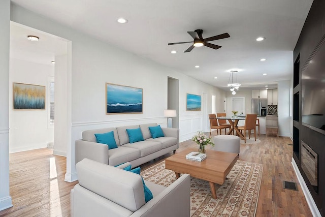 living room featuring light wood-style floors, recessed lighting, visible vents, and a ceiling fan