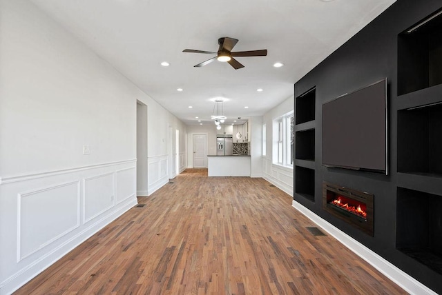 unfurnished living room featuring visible vents, ceiling fan, recessed lighting, light wood-style flooring, and a glass covered fireplace