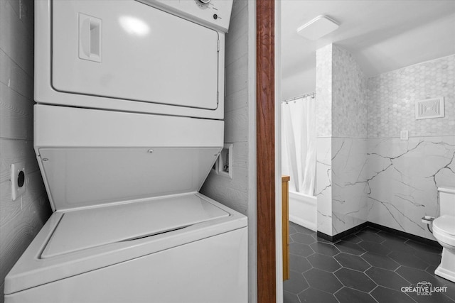 627 S Main St, Montgomery, IL 60538 - clothes washing area with dark tile patterned floors, stacked washer / dryer, and laundry area