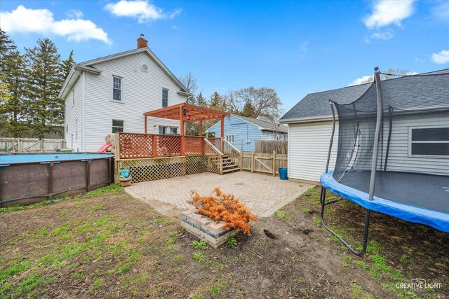 627 S Main St, Montgomery, IL 60538 - back of house with a trampoline, a chimney, fence, a fenced in pool, and a wooden deck
