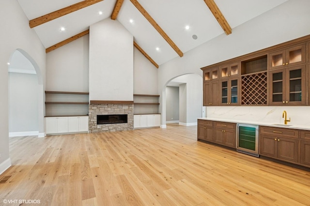 10940 German Church Rd, La Grange, IL 60525 - unfurnished living room with beverage cooler, arched walkways, high vaulted ceiling, beam ceiling, and light wood-type flooring