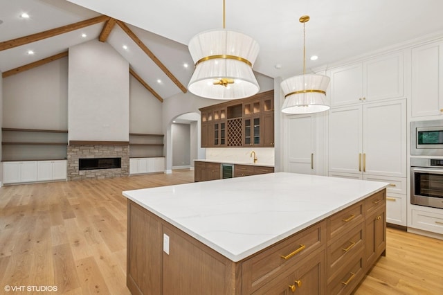 10940 German Church Rd, La Grange, IL 60525 - kitchen with stainless steel appliances, a center island, beamed ceiling, light wood-type flooring, and light stone countertops
