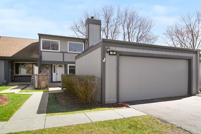 mid-century modern home featuring aphalt driveway, a chimney, and an attached garage