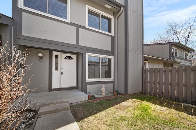 property entrance with fence and stucco siding