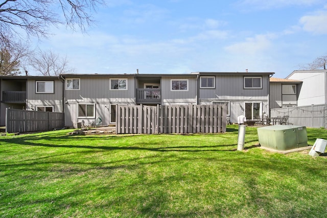 rear view of property featuring fence and a lawn