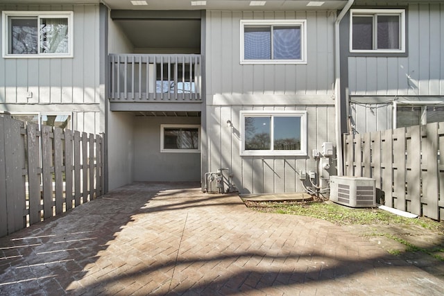 back of house featuring central AC unit, fence, a patio, and a balcony