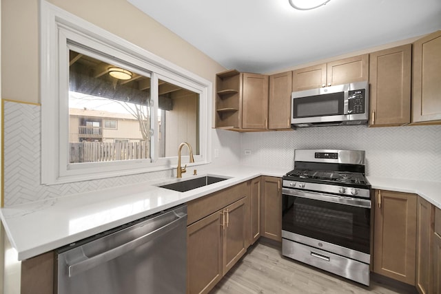 kitchen with open shelves, a sink, light countertops, light wood-style floors, and stainless steel appliances