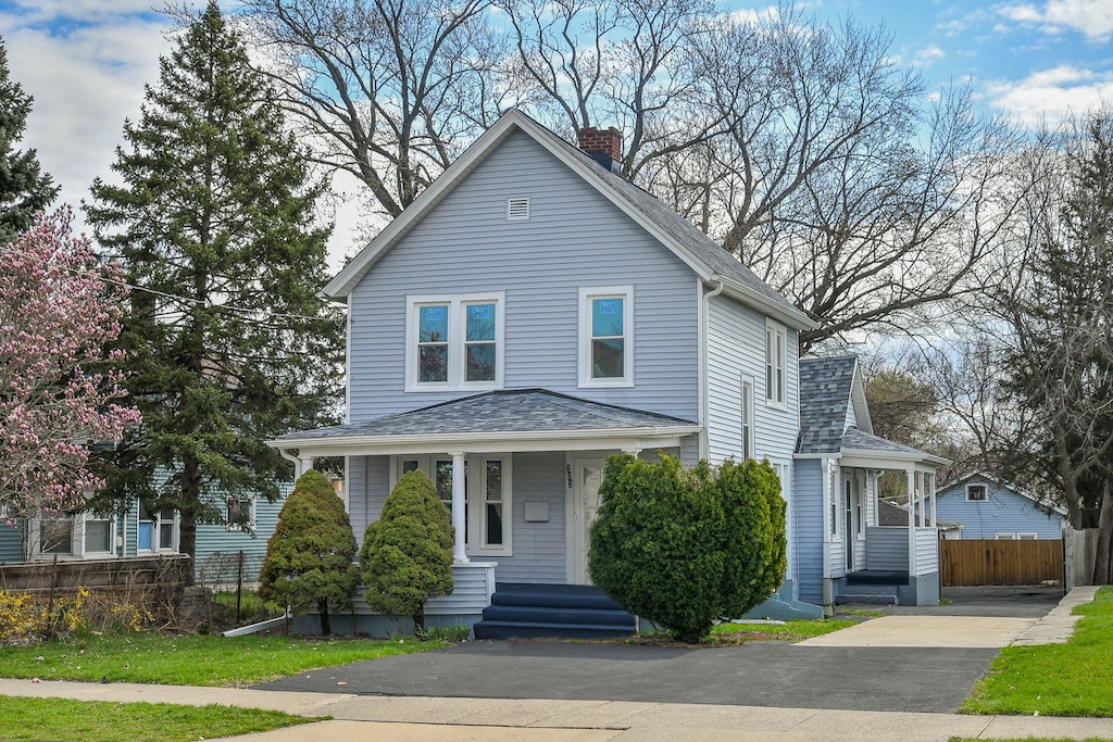 223 N 4th St, Aurora, IL 60505 - view of front facade featuring roof with shingles, a chimney, driveway, and fence