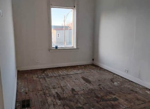 spare room featuring visible vents, hardwood / wood-style flooring, and baseboards