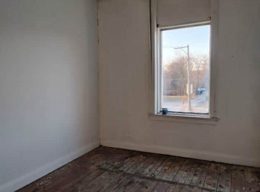 unfurnished room featuring dark wood-type flooring, baseboards, and a healthy amount of sunlight