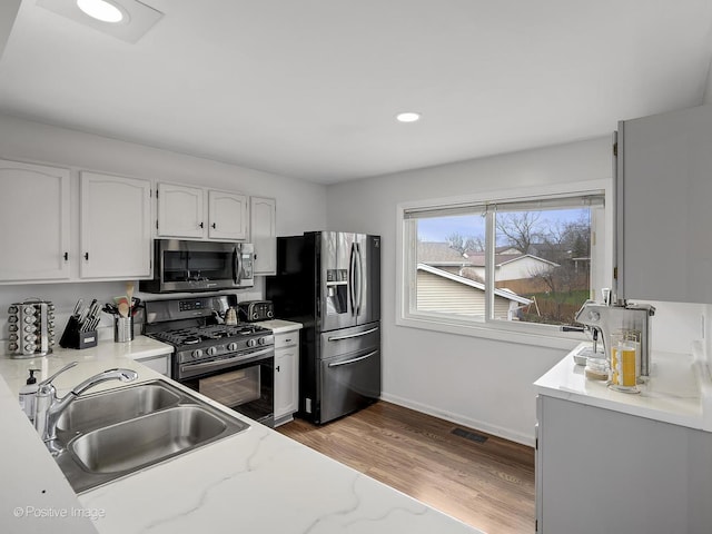 133 Abbeywood Cir, Streamwood, IL 60107 - kitchen with white cabinets, a sink, stainless steel appliances, light wood finished floors, and baseboards