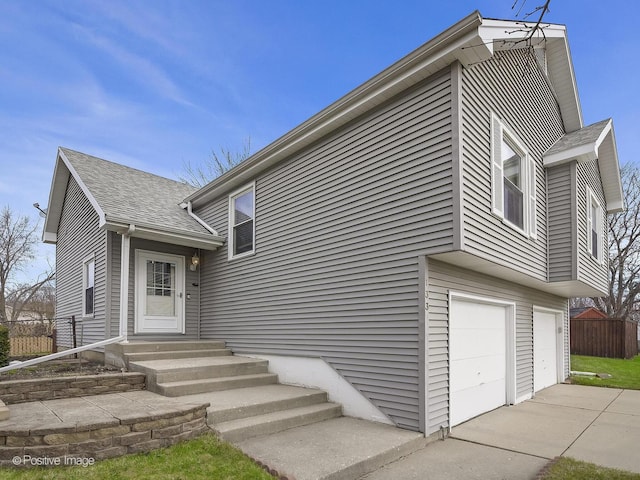 133 Abbeywood Cir, Streamwood, IL 60107 - split level home with a shingled roof, driveway, fence, and an attached garage