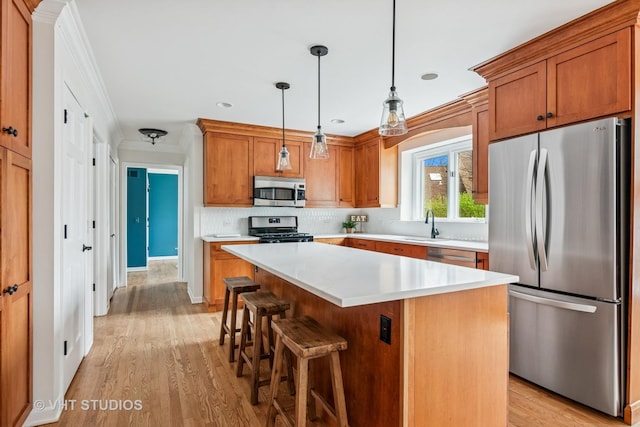 kitchen with appliances with stainless steel finishes, light countertops, brown cabinetry, light wood-style flooring, and decorative backsplash