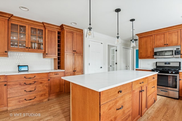 kitchen with appliances with stainless steel finishes, tasteful backsplash, brown cabinets, light wood finished floors, and ornamental molding