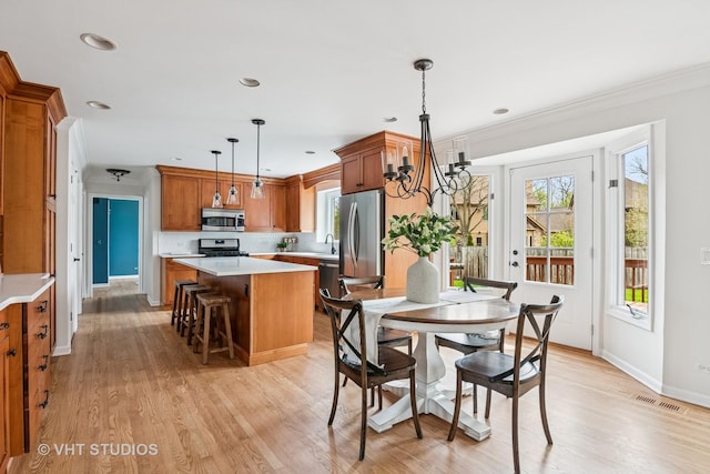 dining area featuring visible vents, light wood-style floors, baseboards, and an inviting chandelier