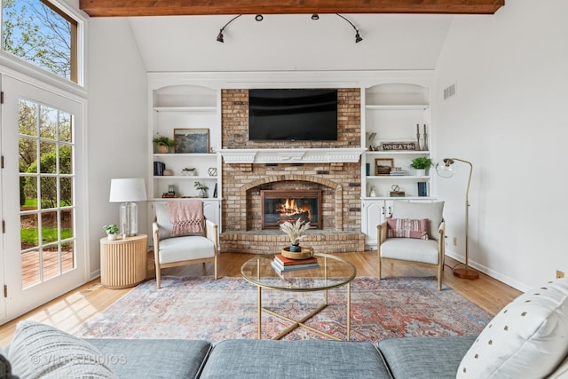 living area featuring visible vents, built in features, wood finished floors, a fireplace, and baseboards
