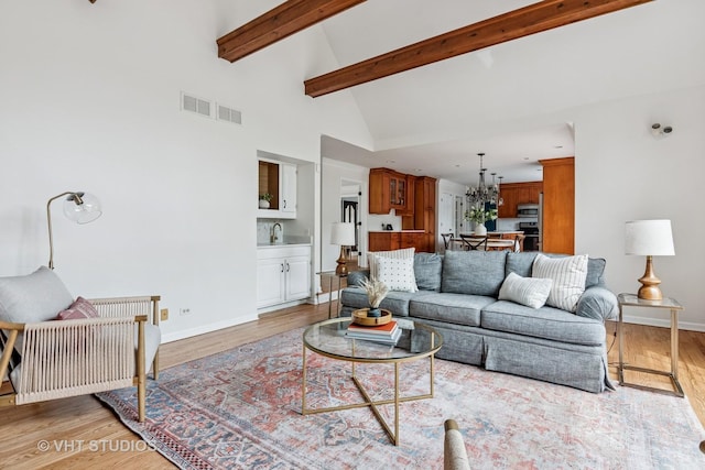 living room featuring baseboards, an inviting chandelier, light wood-style flooring, and visible vents