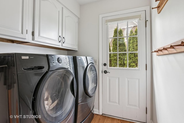 laundry area featuring separate washer and dryer, light wood-type flooring, and cabinet space