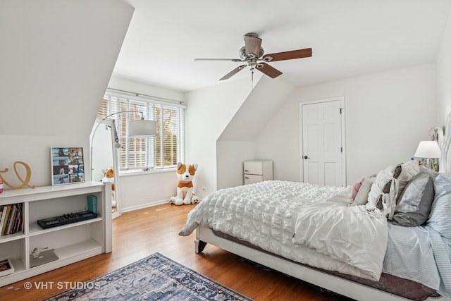 bedroom featuring baseboards, a ceiling fan, light wood-style flooring, and vaulted ceiling