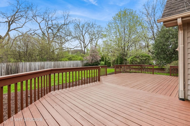 wooden terrace featuring a fenced backyard and a yard