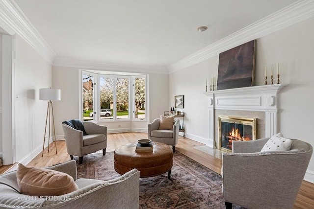living area with ornamental molding, light wood-style flooring, and a premium fireplace