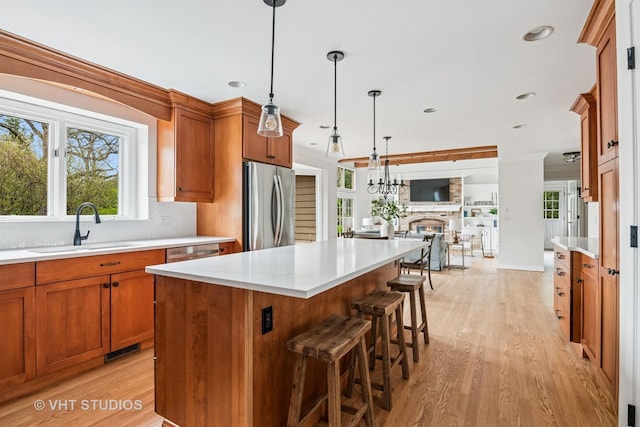 kitchen featuring light wood-type flooring, a sink, light countertops, open floor plan, and stainless steel appliances