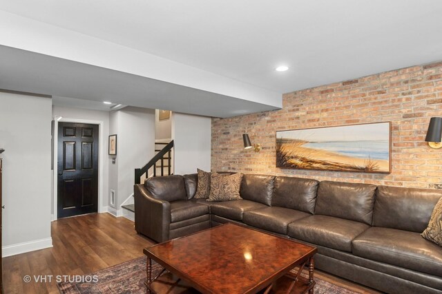 living area with baseboards, wood finished floors, brick wall, stairs, and recessed lighting