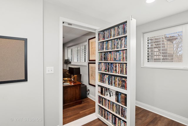 hallway featuring wood finished floors, baseboards, and a desk