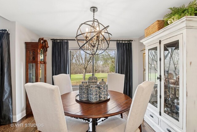 dining space featuring a chandelier, wood finished floors, and baseboards